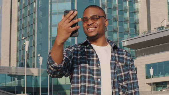 Portrait of Afro American Man in Sunglasses Male Tourist Makes Video Call Mobile Phone App Standing
