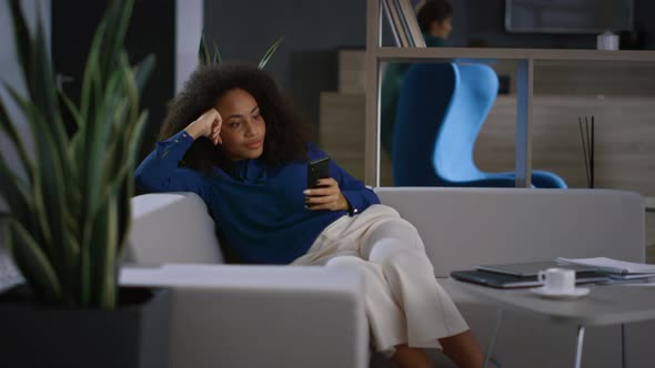 Relaxed Businesswoman Browsing Internet Using Mobile Phone in Modern Office