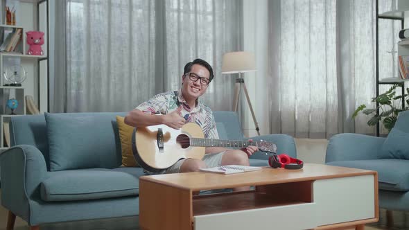 Man Composer With Headphones Smiling And Showing Thumbs Up Gesture To Camera While Playing Guitar