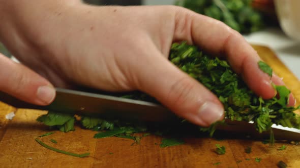 A close-up of the cook slicing parsley. Using a knife and his hand, he kills it from the kitchen