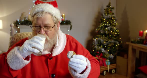 Santa claus relaxing on chair and having sweet food 4k