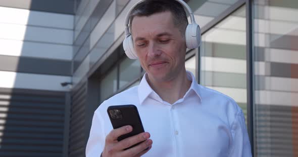 Portrait of 40 Years Old Man Enjoy Listen Music By Wireless Headphones and Smartphone Standing