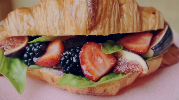 Beautiful Crispy Golden Berry Croissant with Strawberries Blackberries and Basil on Pink Plate