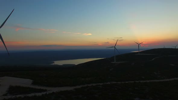 Flying above windmills for the production of electric energy, at sunset