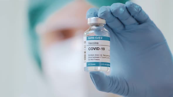 Woman doctor holds in her hand vaccine bottle for COVID-19 new coronavirus