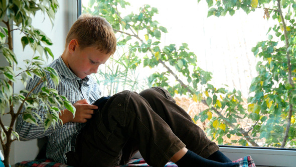 Boy Sitting By A Window Using His Tablet 2