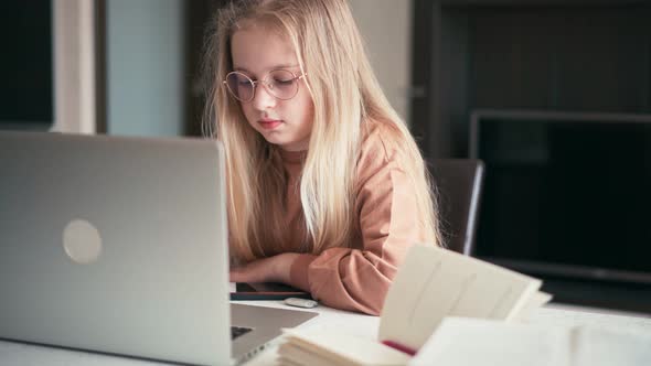 Beautiful 10 Years Old Girl Doing Her Homework Using a Laptop