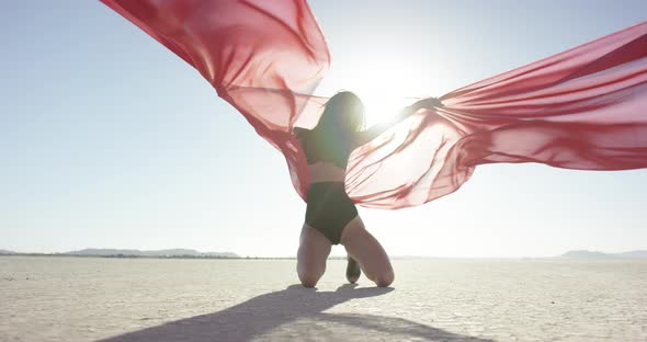 Girl with a fabric dancing in the desert