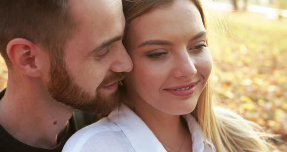 Close View of Happy Boyfriend Kisses His Lovely Girl in Embraces in Autumn Park