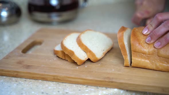 Close-up, a woman cuts bread into pieces to make toast for breakfast