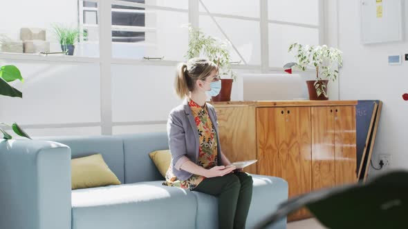 Office colleagues wearing face masks greeting each other by touching elbows at office