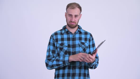 Stressed Bearded Hipster Man Showing Clipboard and Giving Thumbs Down