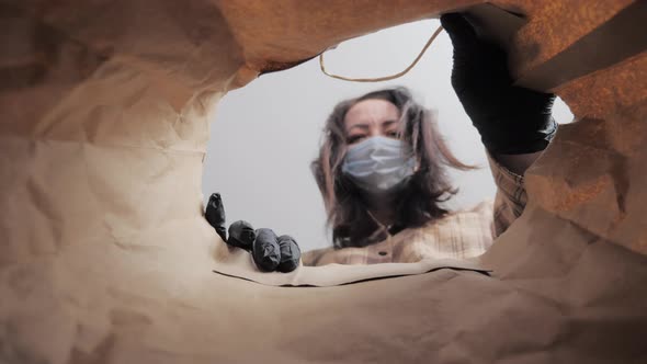 Young Woman with Personal Protective Equipment Gloves and a Medical Mask on Facecarefully Opens Box