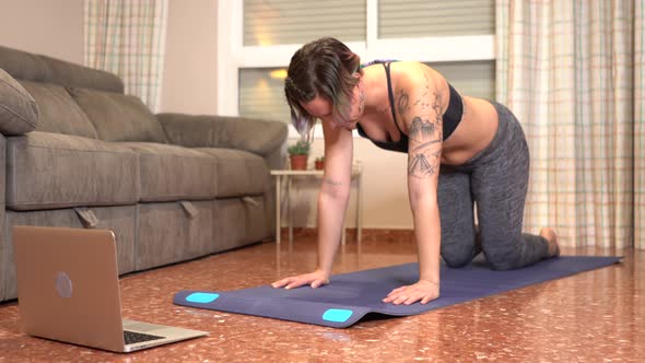 Woman doing lower back during online class at home