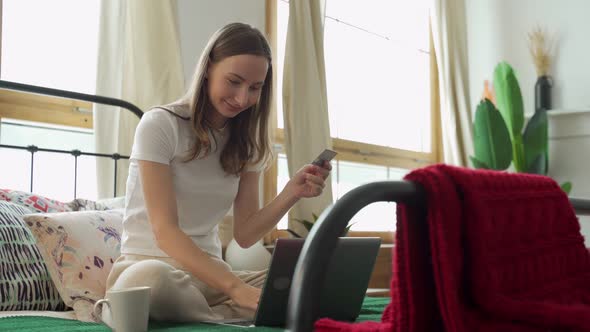 Woman Holding a Credit Card in Her Hand Is Trying To Buy Something Online While Lying on the Couch