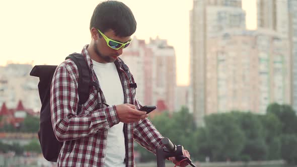 Male Use Phone Surfing Internet Online Shopping at Smartphone Outside in Summer on River Embankment