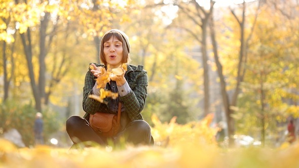 Girl Is Blowing Out Autumn Leaves