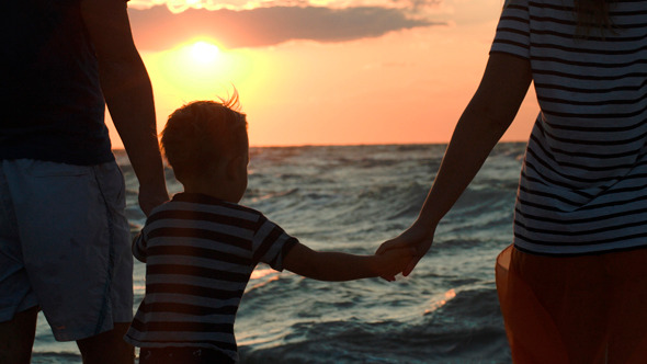 Family Looking At Sunset Holding Hands