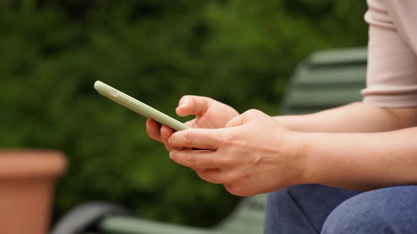 Woman Holds a Smartphone in Her Hands and Views Publications on Social Networks