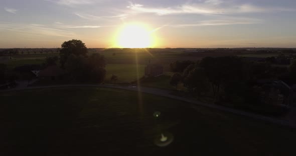 A drone shot flying to the left, with the sun going down behind a church