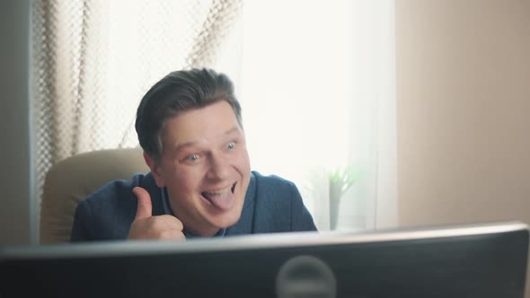 Joyful Man Showing Tongue While Sitting at Computer