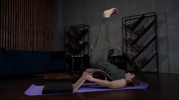 a Woman is Lying on a Sports Mat Against a Gray Wall