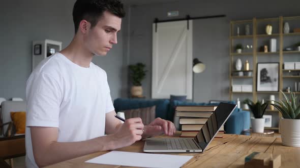 Man Writing on Documents While Sitting on Desk