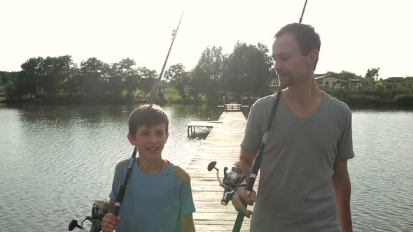 Happy Dad and Son with Rods Going Fishing on Pond