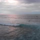 Aerial flyover view of waves crashing during sunset with people swimming in the sea in Bali - VideoHive Item for Sale