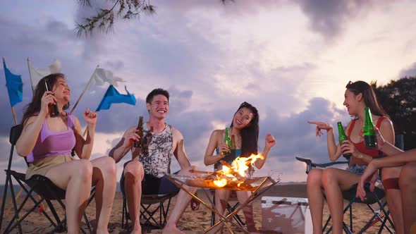 Group of Asian young man and woman having party on the beach at night.