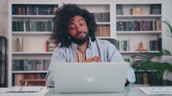 Focused Arabian Man Student Makes Notes in Notebook Watching Webinar on Laptop