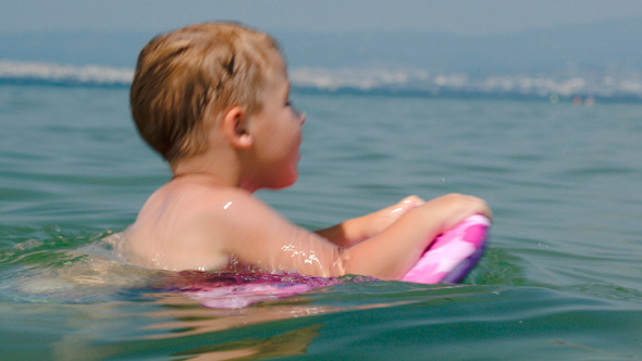 Little Boy Trying To Swim On Board In The Sea