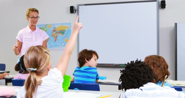 School kids raising hand in classroom