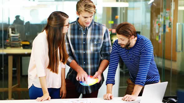 Graphic designers interacting with each other while working in office