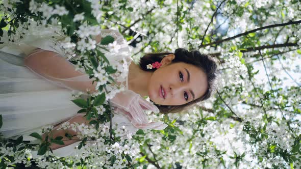 Fashion Portrait of a Young Beautiful Woman in a White Dress Standing and Posing Next to a Cherry