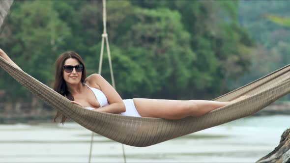 Young Beautiful Woman in Sunglasses Relaxing on the Hammock on Tropical Beach