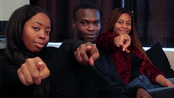 Three African Friends Point To Camera with Finger and Smile in Living Room