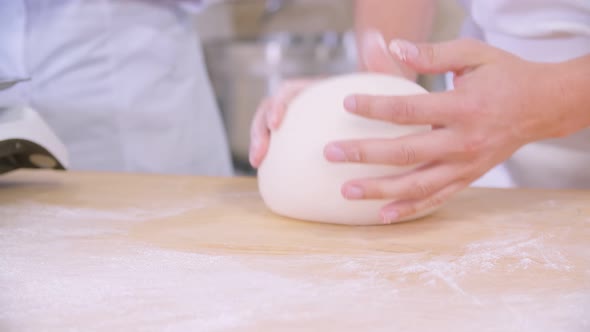 Closeup of Dough Kneaded By Baker on a Wooden Board Sprinkled with Flour