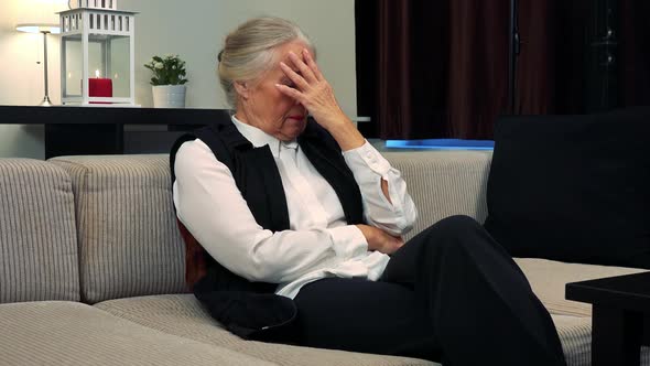 Old Unhappy Caucasian Woman Worries and Cries in Living Room