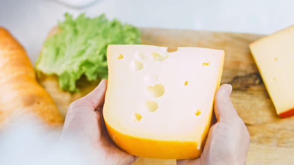 The Woman Holds in Her Hands a Piece of Cheese with Holes