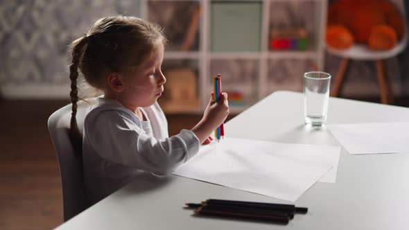 Little Artist Gathers Crayons in Bunch to Draw at Table