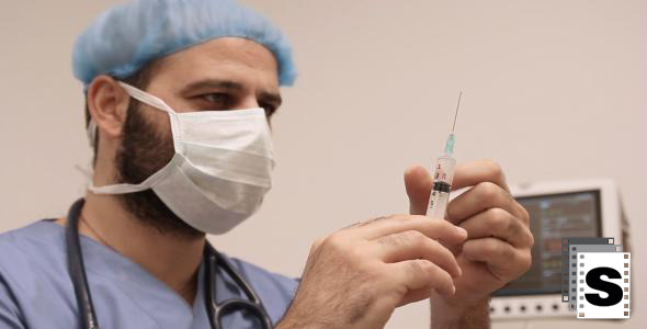 Male Surgeon Checks Medical Syringe 
