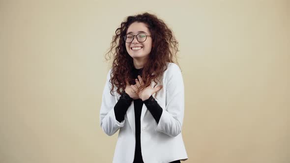 Cheerful Young Woman with Curly Hair Laughing Out Loud Leaning Forward and Pointing to the Room