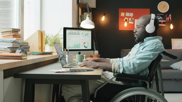 Black Man in Wheelchair Enjoying Music and Working at Home