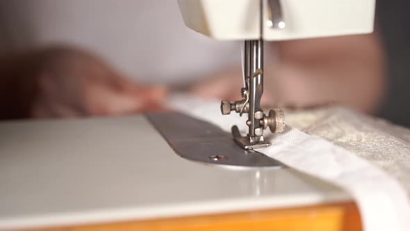 Close Up of Sewing Machine with Women's Hands on Table