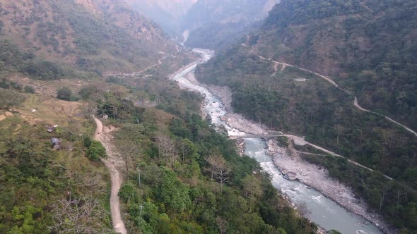 Aerial view dirt road cutting through mountain valley along the Marsyangdi River