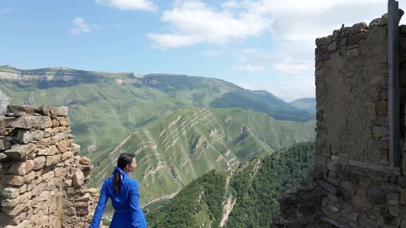 Woman in a Blue Long Dress Stands on Top of the Roof on an Abandoned Village