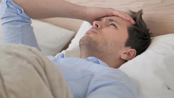 Tense Young Man with Headache Lying in Bed