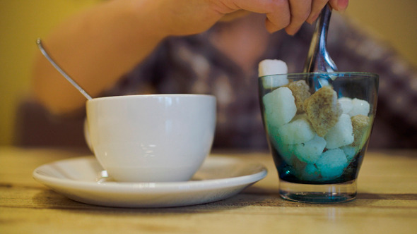 Woman Putting Sugar Into Tea Cup Using Tongs