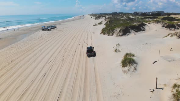 Drone following black suv on Outer Banks Corolla 4x4 beach.